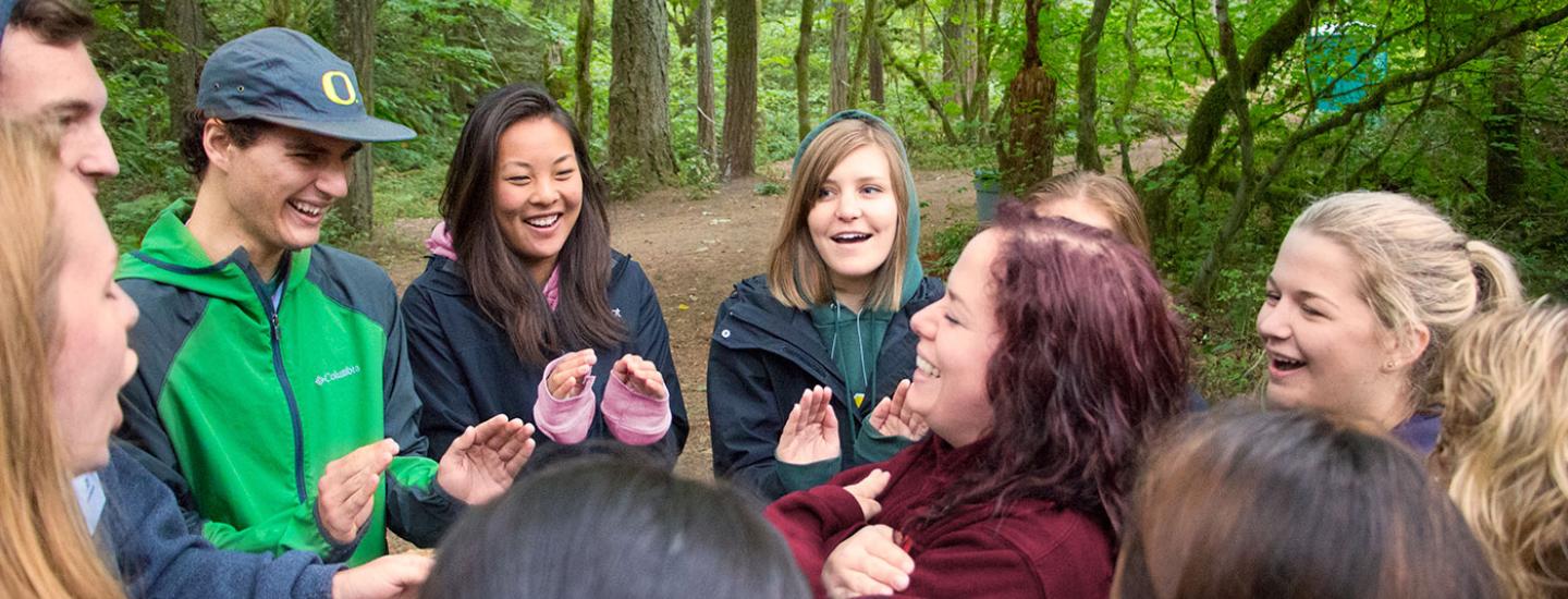 Students standing in a circle playing a trust game with the person in the center.