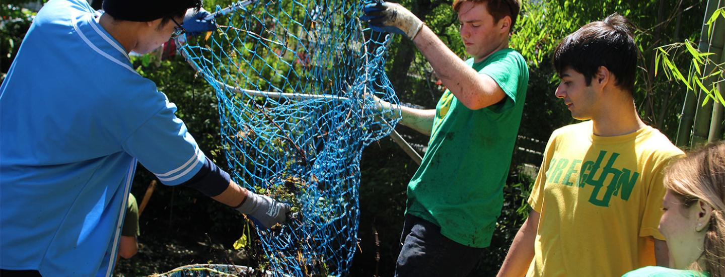Four students removing items from a net as they clean up the nearby canal.